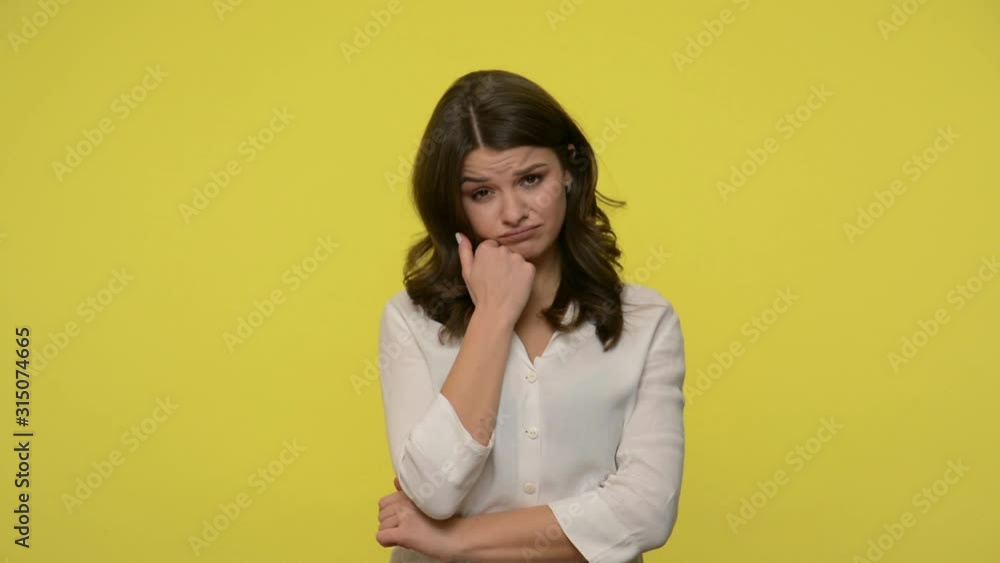 Bored young woman with brunette hair in blouse leaning on hand and listening to talk without interest with dull facial expression, waving head saying no. studio shot isolated on yellow background Bored young woman with brunette hair in blouse leaning on hand and listening to talk without interest with dull facial expression, waving head saying no. studio shot isolated on yellow background