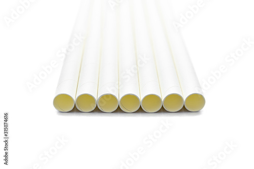 Close up white paper straws laying flat isolated on white background.