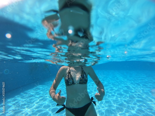 Woman stretching out hand towards camera underwater.