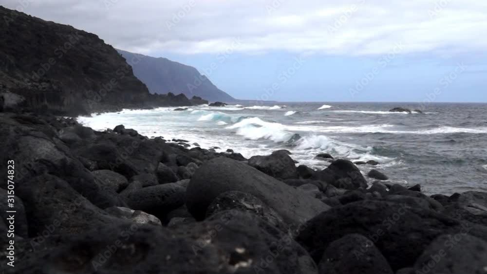 Black lava stone beach and cliffs and ocean along El Golfo valley in El Hierro, Canary Islands, Spain Black lava stone beach and cliffs and ocean along El Golfo valley in El Hierro, Canary Islands, Spain