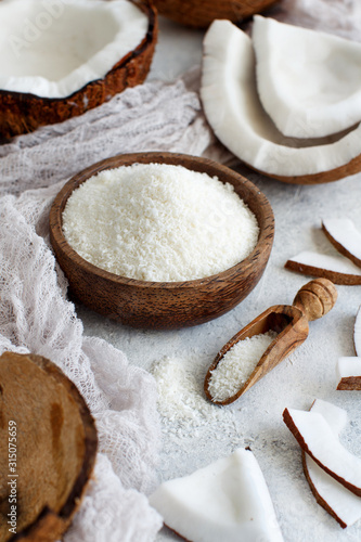 Coconut flour in a wooden bowl with a spoon close up