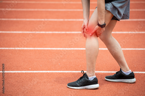 Close up of runner woman holding her leg, suffuring from ITB Syndrome caused by altered running biomechanics due to underlying muscular imbalances. photo