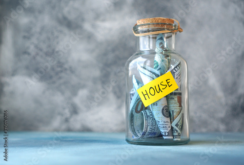 Housing. Money for house concept with glass jar labeled house filled with money.