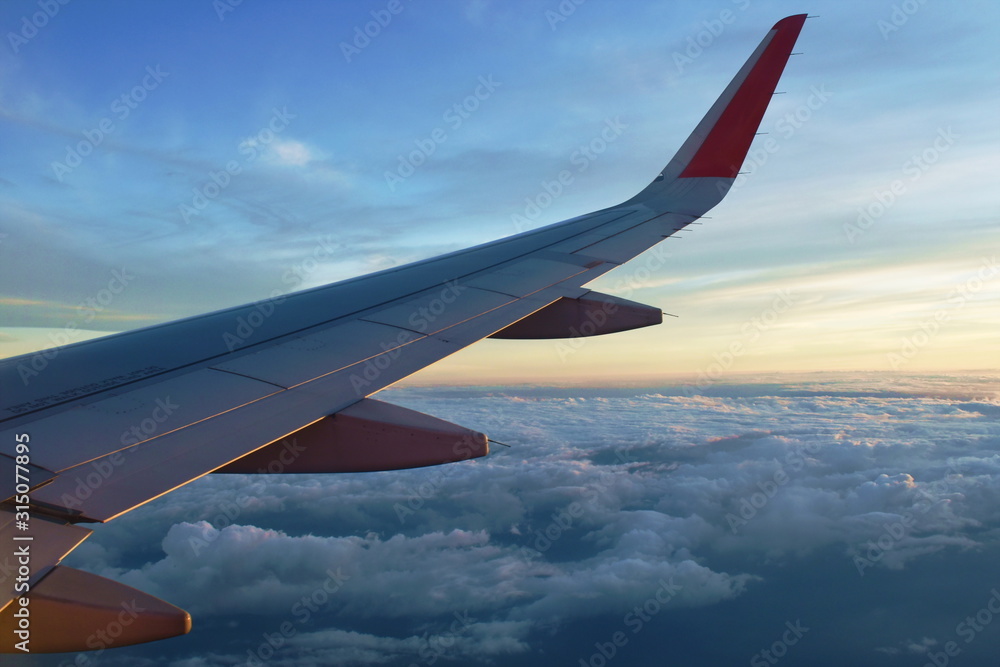 Obraz premium plane wing and cloud floating on sky through window frame on sunset