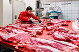 Butcher or meat cutter preparing raw calf meat at the slaughterhouse or abattoir