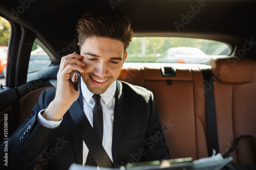 Image of young businesslike man in suit talking on cellphone in car © Drobot Dean