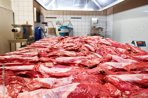 Fresh raw beef meat on the table and meat mincing equipments in the background in a slaughterhouse photo