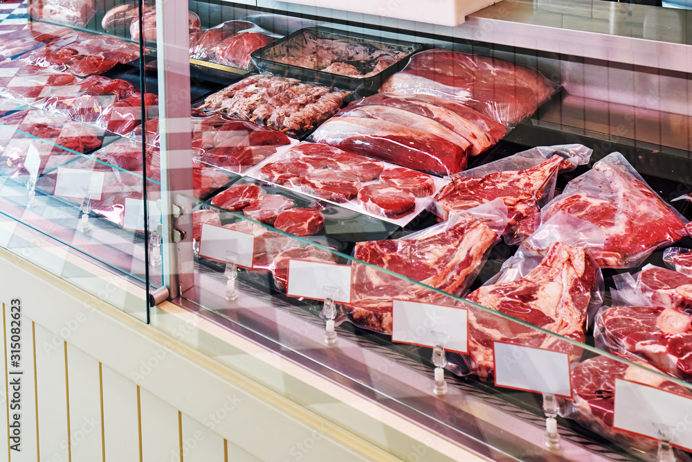 Selection of raw fresh veal meat in the refrigerated display of a butcher shop