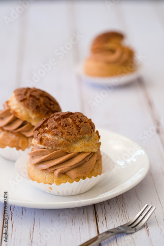 Homemade choux cream or cream puffs with tea cream on wooden background.