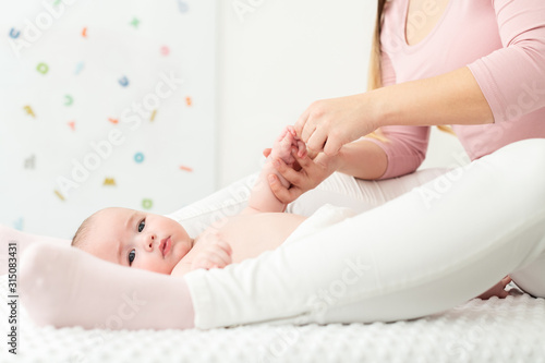 Baby massage background. Mother gently massaging her baby boy. Baby lying on back and looking at camera during massage.