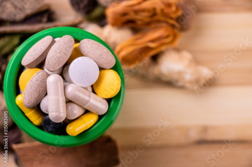 Top view macro shot of herbal pills and tablets arranged with spices on a red stone. Unani medicines concept. photo