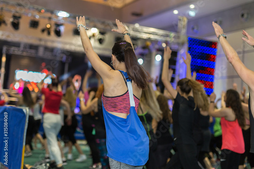 Fitness Workout in Gym: People doing Exercises in Class with Music and Teacher on Stage