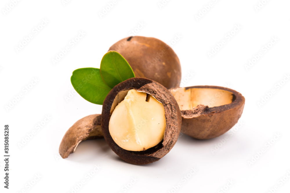 Macadamia nut with pieces and green leaves isolated on a white background Macadamia nut with pieces and green leaves isolated on a white background