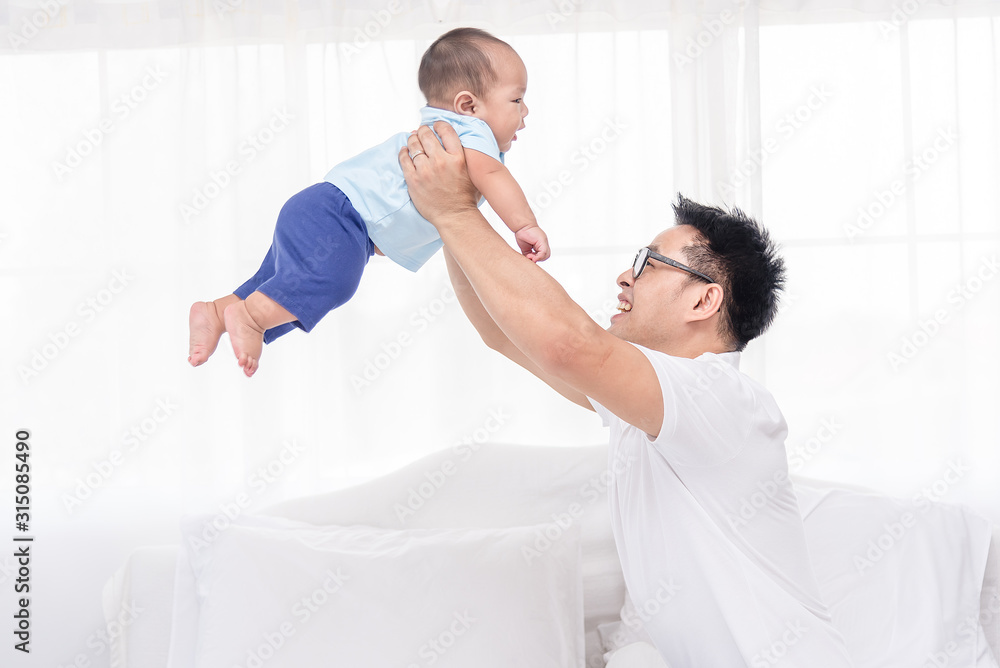 Young handsome Asian father happily playing with his 5 months baby boys. Healthy newborn baby boys with father in bed room. Young handsome Asian father happily playing with his 5 months baby boys. Healthy newborn baby boys with father in bed room.