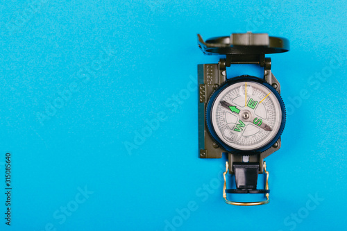 metal navigation travel compass on a blue background. search for a way. point of view