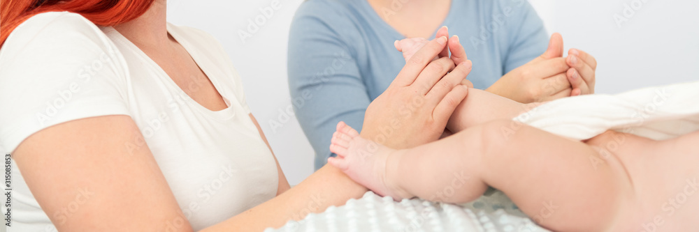 Female massage therapist teaching young mother how to massage her newborn baby boy. Baby massage concept. Cropped shot close up on hands web banner. Female massage therapist teaching young mother how to massage her newborn baby boy. Baby massage concept. Cropped shot close up on hands web banner.