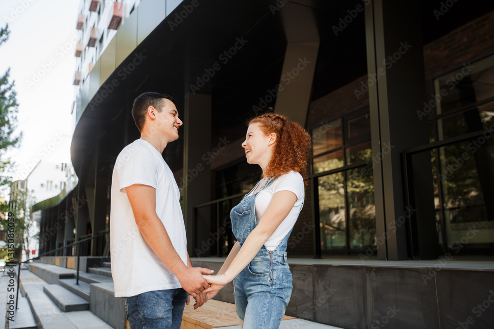 A young couple is walking in the modern city, holding hands. Inspect the conceptual archeology.