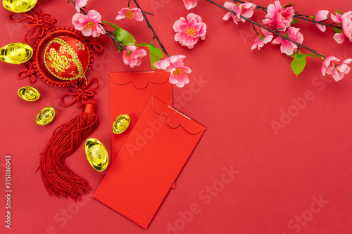 Chinese character means fortune and luck.Accessories on Lunar New Year & Chinese New Year vacation concept background.Red envelop and pink flower with orange on modern red wallpaper.copy space.