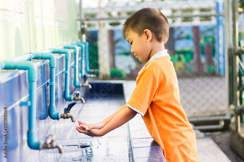 Asian student​ child boy washing his hands before eating food and after play the toys at the washing bowl at the school. A boy aged of 5-6​ years old. Health care and kid concept. 