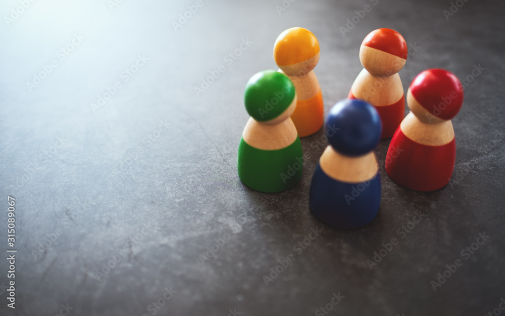 Group of wooden figurines in different colors standing in a circle for the concepts of diversity, equality and business Group of wooden figurines in different colors standing in a circle for the concepts of diversity, equality and business