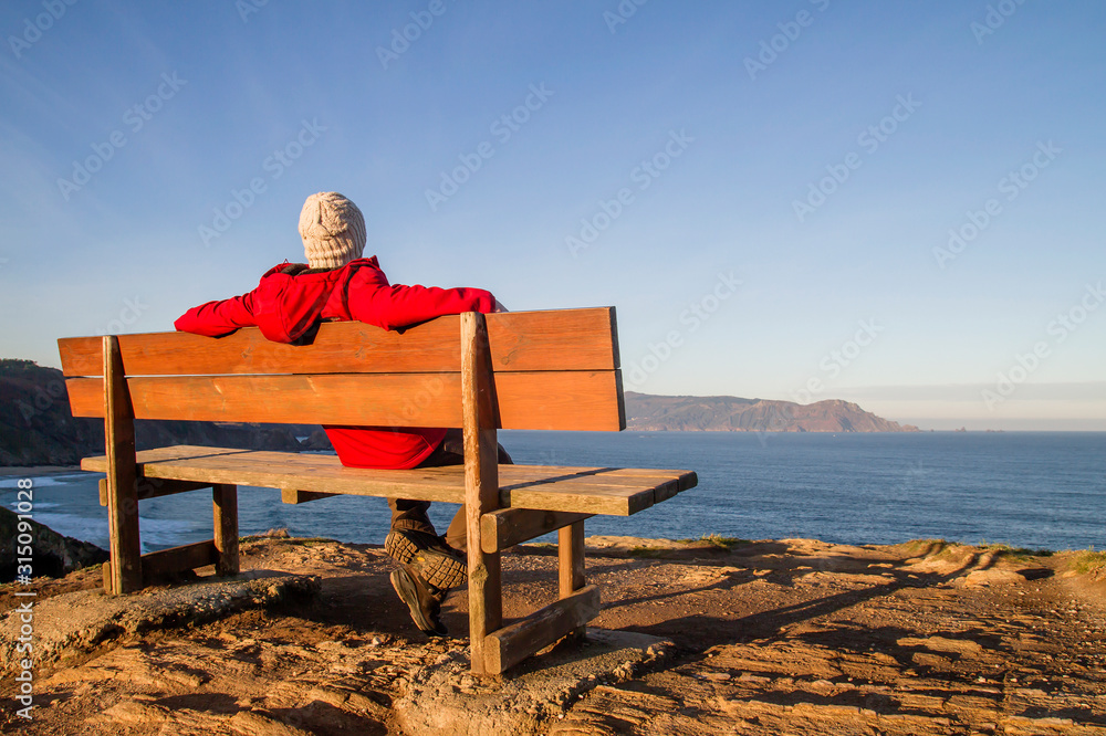 Man relaxin on a wooden bench by the sea