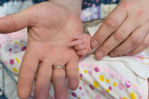 hands of a newborn baby and dad