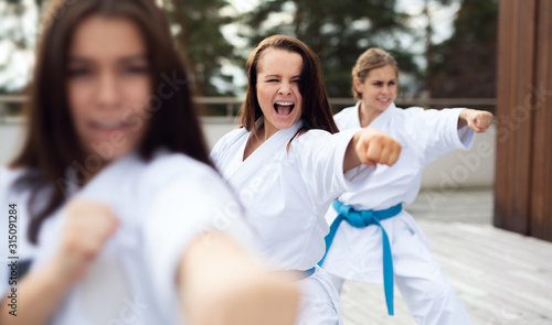 Group of young women practising karate outdoors on terrace.
