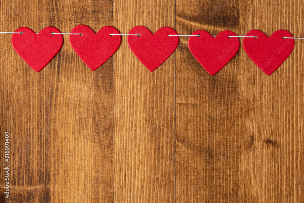 Bright red hearts hang on a rope on a wooden background, flat lay, top view, copy space. Background with red hearts for Valentine's day, wedding, holiday. Love and romance background. Bright red hearts hang on a rope on a wooden background, flat lay, top view, copy space. Background with red hearts for Valentine's day, wedding, holiday. Love and romance background.