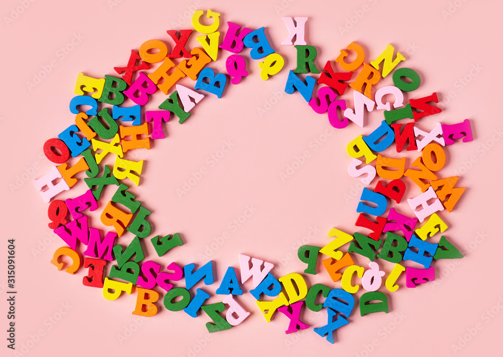 Multicolored wooden alphabet on a pink background, top view, flat lay, free space for text. Preschool or back to school concept.
