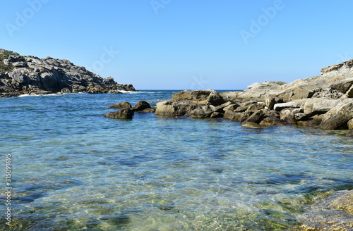 Beach with rocks, clear water and blue sky. Galicia, Spain.