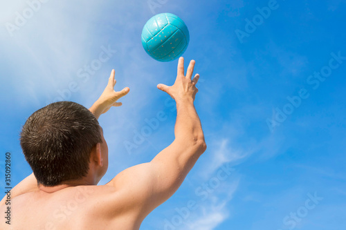Close-up of a player with a volleyball ball. The view from the back.