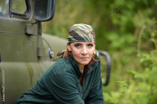 Woman wearing camouflage bandana against the backdrop of UAZ.