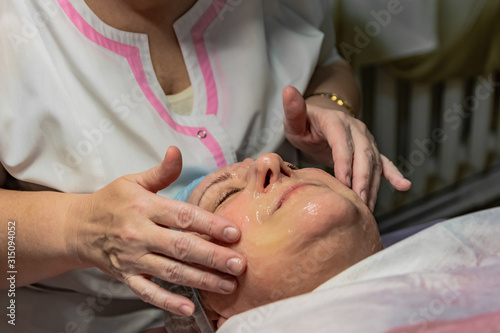 Non-invasive face carboxytherapy in a beauty salon. It is performed for an age woman. Non-injection transdermal administration of carbon dioxide under the skin. Apply the gel to the face.