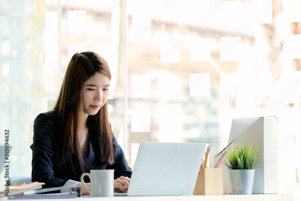 Beautiful young Asian girl working at modern office with a laptop computer for business financial analysis Beautiful young Asian girl working at modern office with a laptop computer for business financial analysis