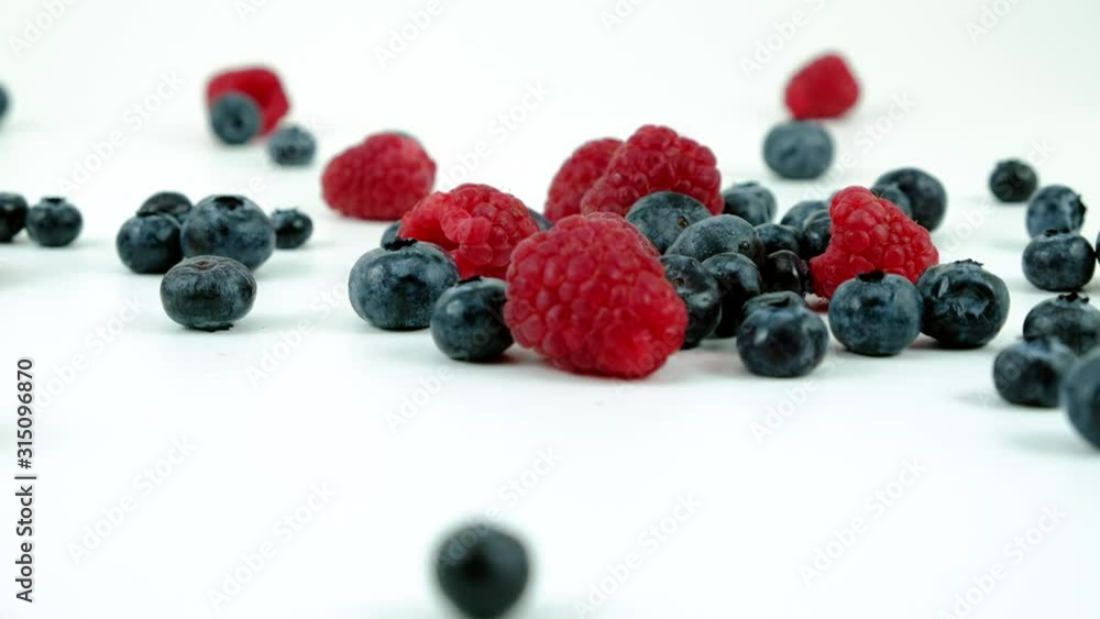 blueberries and raspberries falling from above blueberries and raspberries falling from above