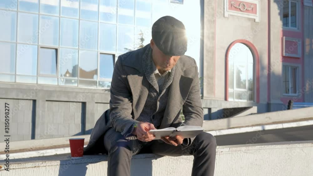 Young male read book outdoorsom the street Young male read book outdoorsom the street
