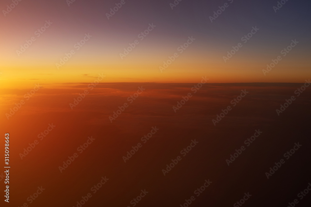Beautiful view of sunset sky above clouds from airplane.