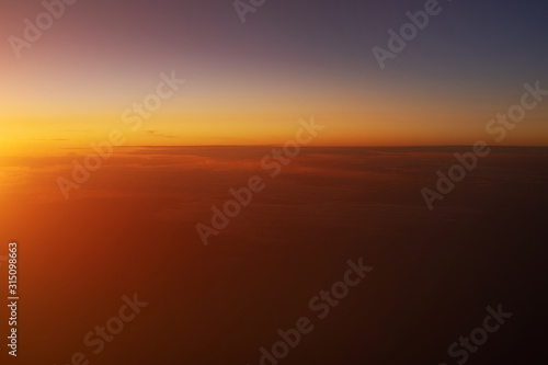 Beautiful view of sunset sky above clouds from airplane.