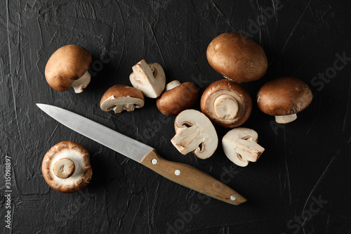 Champignon mushrooms and knife on black background, top view