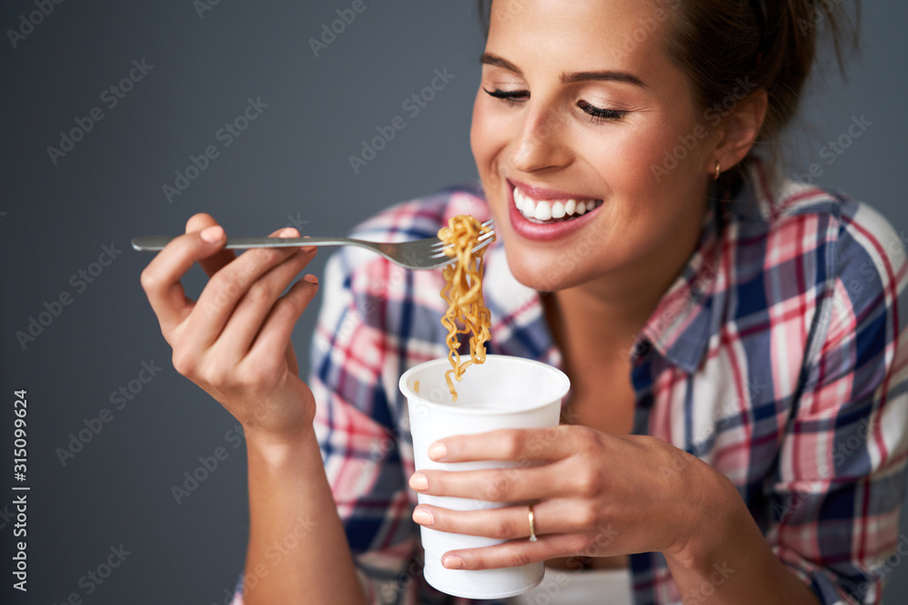 Hungry student eating noodle while learning at home Hungry student eating noodle while learning at home