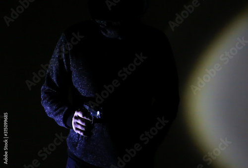 Man robber with gun. Shadow in the spotlight. Criminal concept.