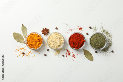Bowls with different spices on white background, top view