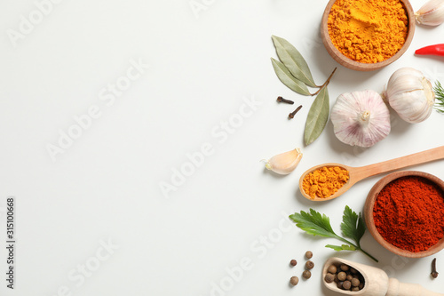 Fototapeta Naklejka Na Ścianę i Meble -  Spoons and bowls with different spices and ingredients on white background, space for text