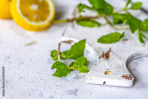 Photo of fresh mint leaves on a cutting board with a knife. Lemon and mint on a cutting board. Peppermint. Ingredients for summer cocktails and lemonade. Macro. Still life. Image.