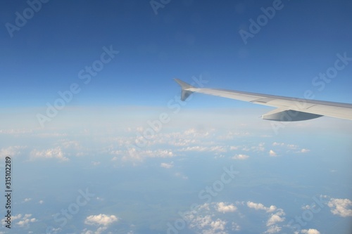 The wing of a jet plane flying in the blue sky above the clouds.View from the passenger window