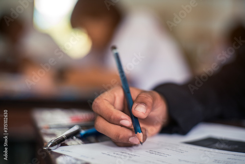 Hand of Student doing test or exam  in classroom of school with stress photo
