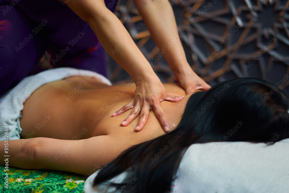 Obraz premium Thai massage, a girl is given a massage on her back, a girl is lying on her stomach, a masseur is on her