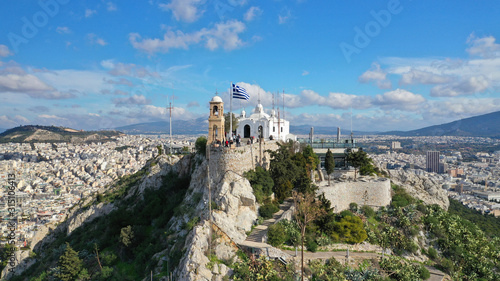 Aerial drone photo of iconic chapel of Saint George on top of Lycabettus hill with beautiful deep blue sky and clouds, Athens, Attica, Greece