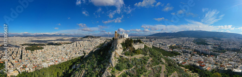 Aerial drone photo of iconic chapel of Saint George on top of Lycabettus hill with beautiful deep blue sky and clouds, Athens, Attica, Greece