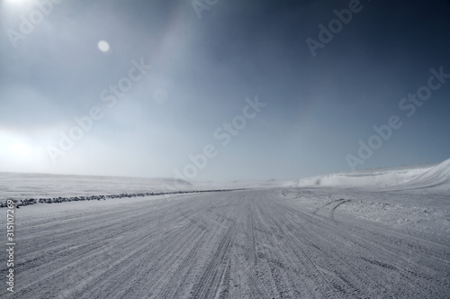 Partial sundog and winter ice road in the high arctic with a blue sky in the background, near Cambridge Bay, Nunavut, Canada